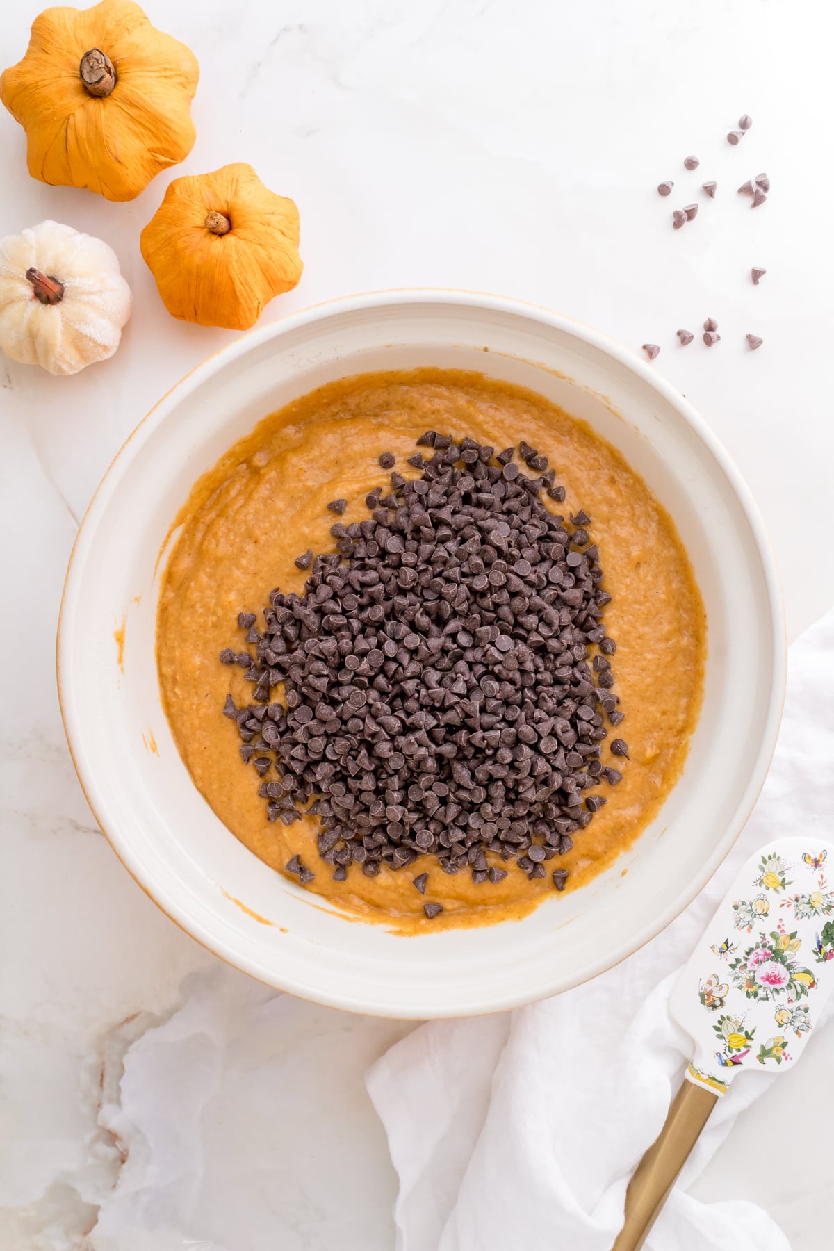 adding mini chocolate chips to pumpkin muffin batter.