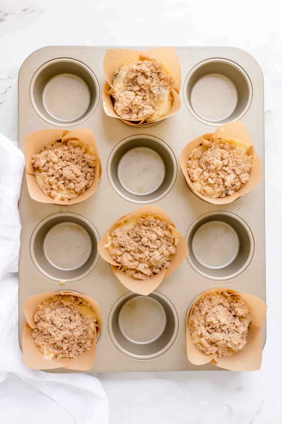 muffin pan filled with discard blueberry muffin batter and streusel.