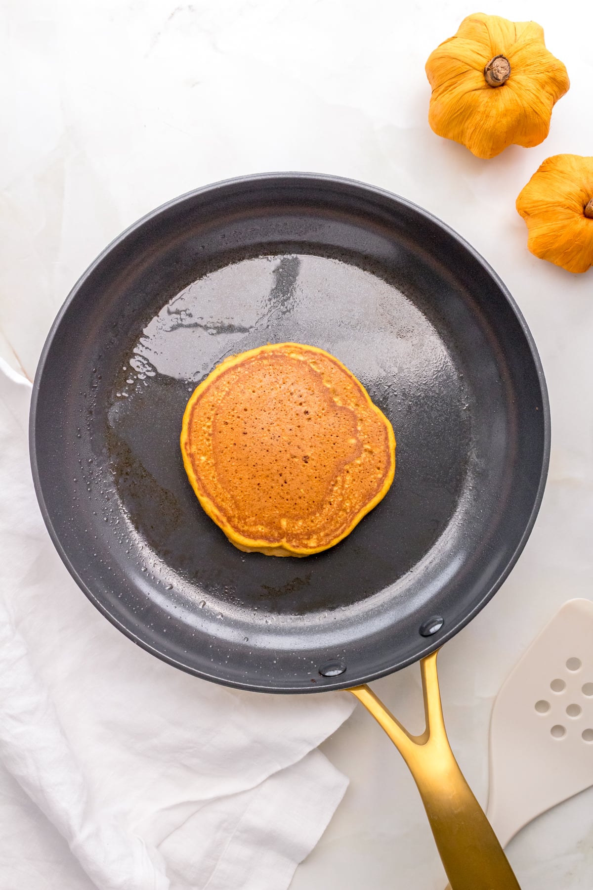 pumpkin pancake cooking in frying pan.