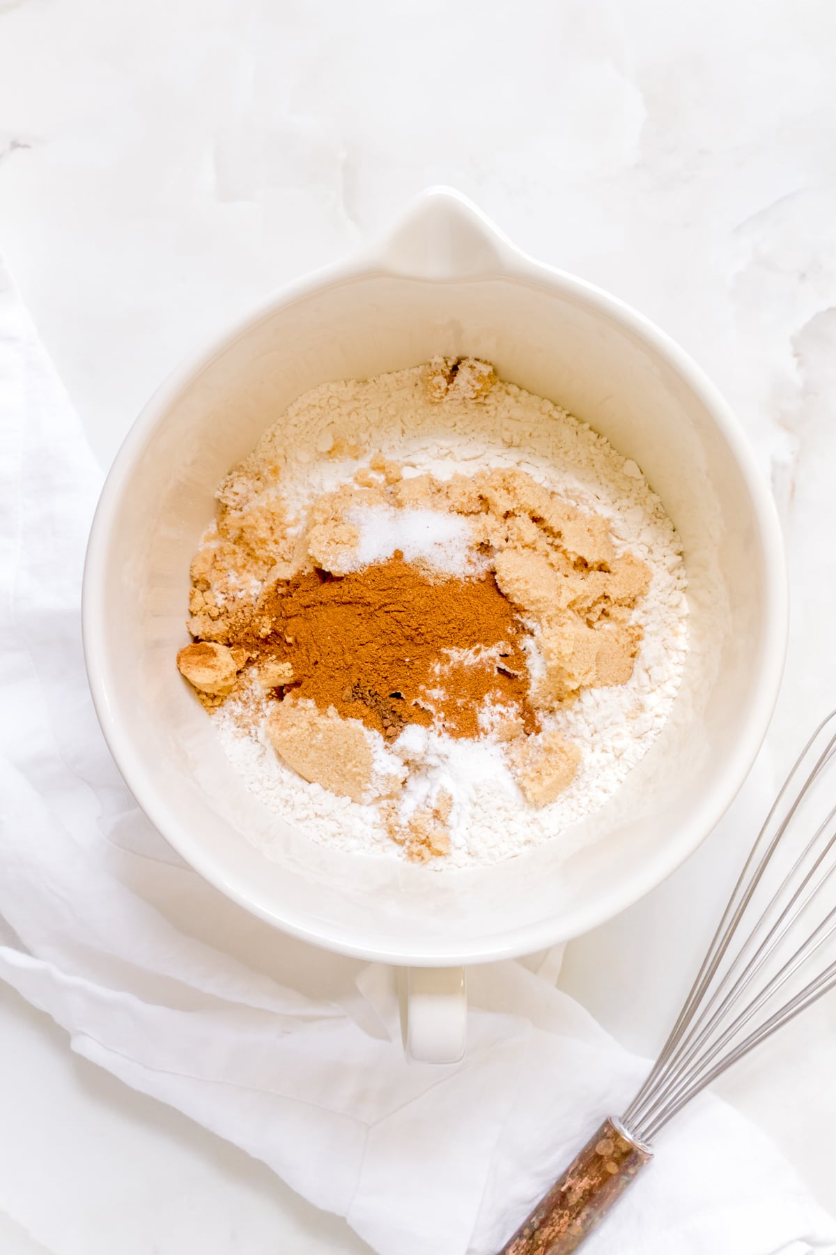 dry ingredients for apple cider donuts in white mixing bowl.