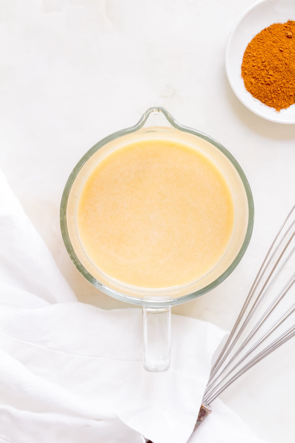 wet ingredients whisked together in glass measuring cup for baked apple cider donuts.