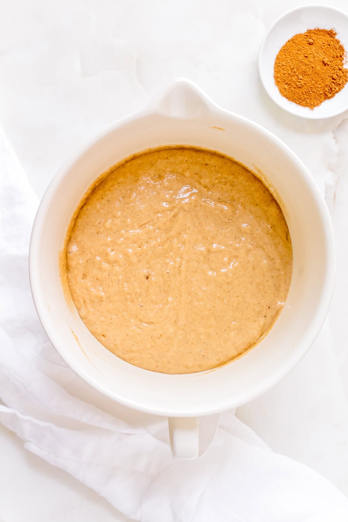 batter for baked apple cider donuts in white mixing bowl.