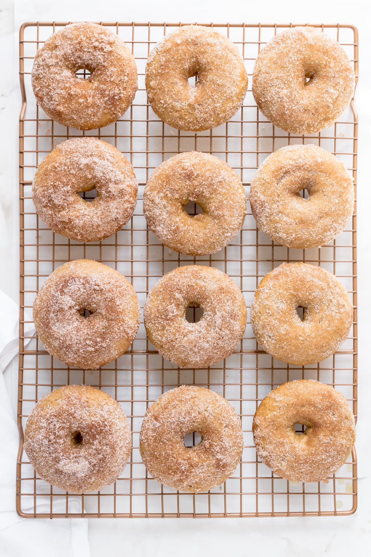 baked apple cider donuts on cooling rack coated with cinnamon and sugar.