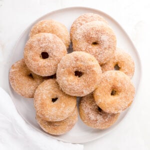 apple cider donuts arranged on a white, round platter.