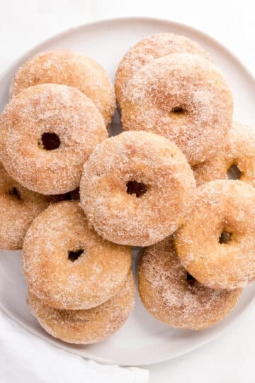 apple cider donuts arranged on a white, round platter.