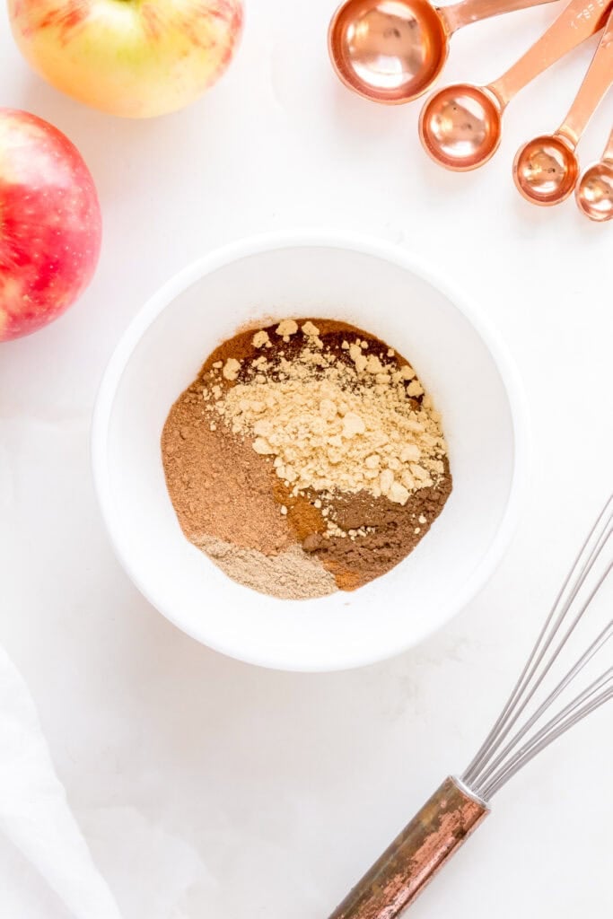 ingredients for apple pie spice in a white mixing bowl.