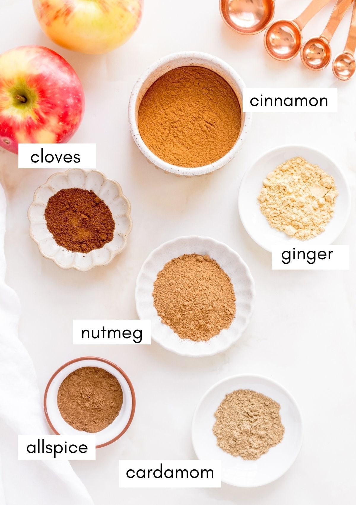 labels white bowls of ground spices for homemade apple pie spice.