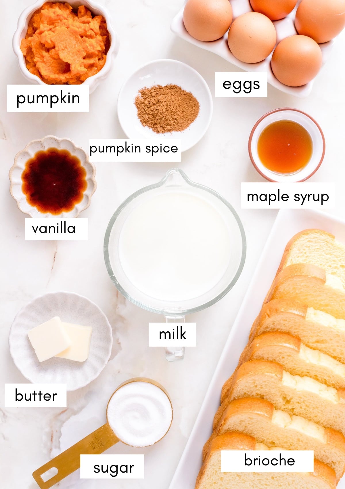 labeled ingredients for pumpkin French toast in small bowls on a white background.